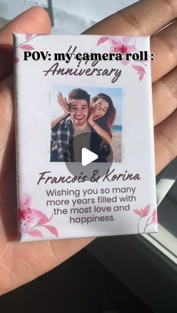 Hand holding a single anniversary photo magnet beside a wrapped gift