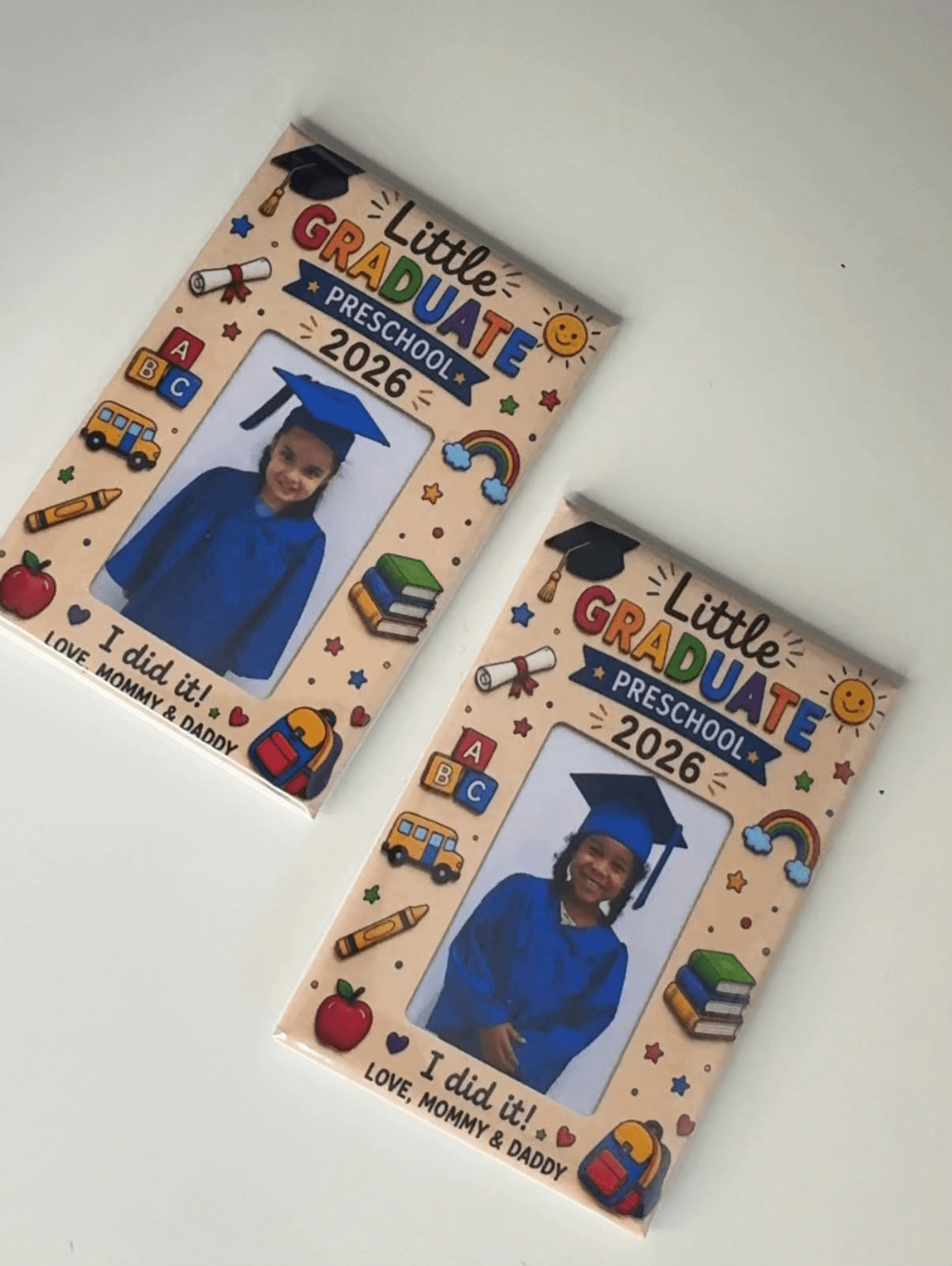 Two handmade preschool graduation photo magnets with blue cap-and-gown portraits and colourful Little Graduate 2026 designs